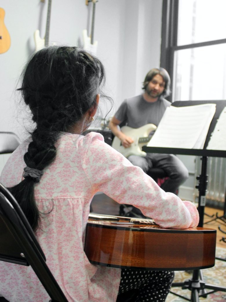 A student learning guitar at Rhythm Music Schools